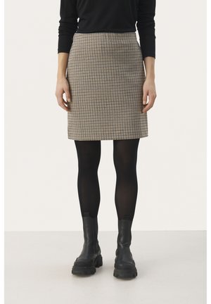 Jupe mini à carreaux en beige et marron, avec une coupe droite. Portée avec des collants noirs et des bottes noires mi-mollet. Texture du tissu lisse.