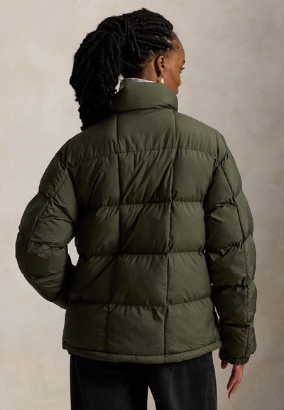 Olive žalia pūsta striukė, pasižyminti siuvinėtu raštu, aukšta apykakle ir elastinėmis rankogalių apdailomis. Medžiaga atrodo lygi ir turi minkštą tekstūrą.