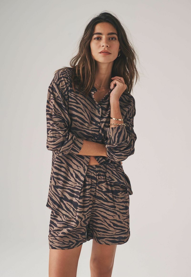 Conjunto de camisa y pantalones cortos de rayas de tigre marrón y negro, con un corte relajado, cierre de botones en la parte delantera y tejido texturizado.