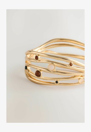 Gouden armband met in elkaar verweven strengen, met vier stenen in beige, bruin en zwart. Glad metaal met een licht gestructureerde afwerking.
