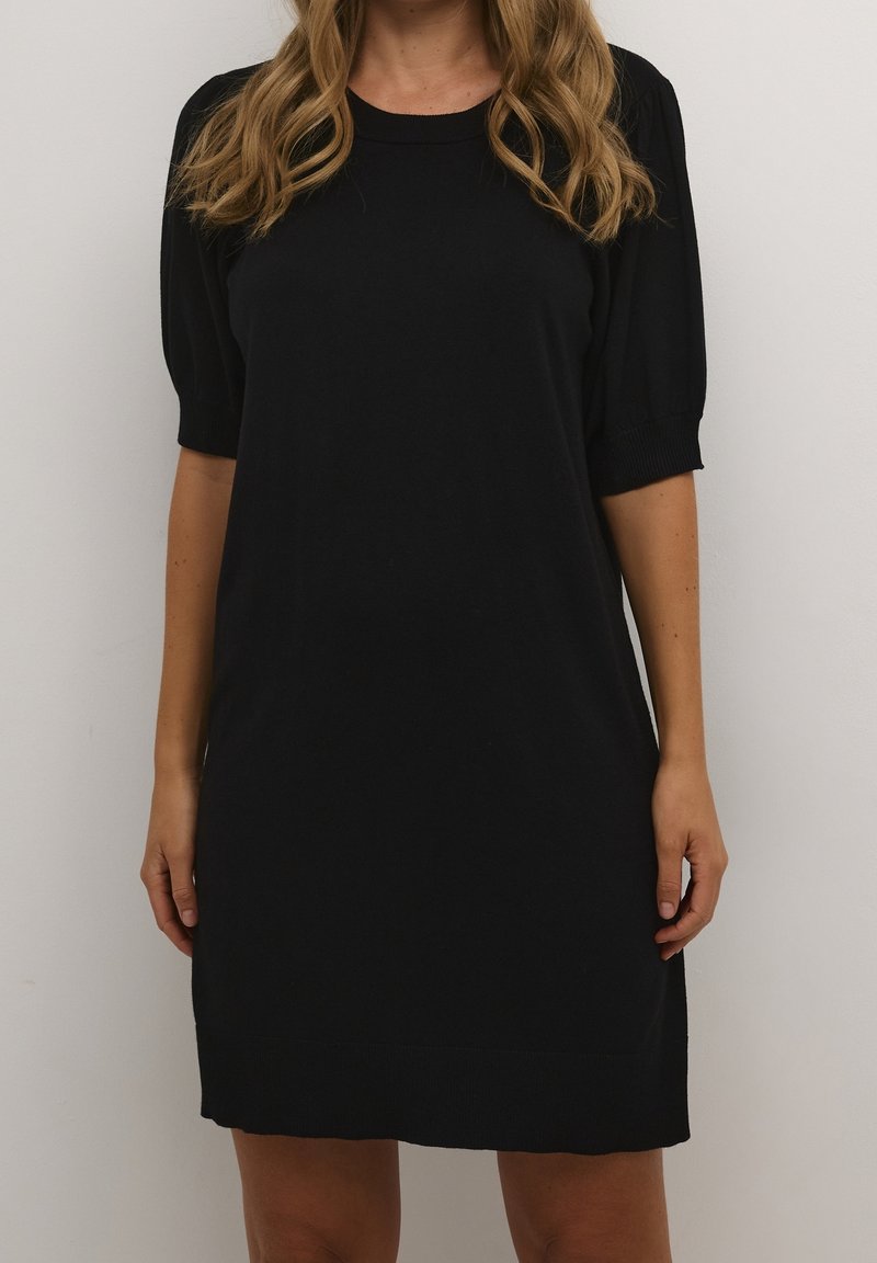 Abito nero in maglia con maniche a sbuffo corte, scollatura rotonda e una vestibilità comoda. L'orlo è leggermente arrotondato, creando una silhouette semplice e moderna.