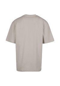 T-shirt à manches courtes en coton beige clair, doté d'un col rond et d'une coupe décontractée, avec une texture lisse et sans motifs visibles.