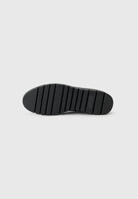 Suela de zapato negra con una superficie texturizada, que presenta canales horizontales y una puntera redondeada. Marca visible en la entresuela.