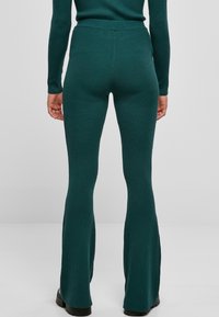 Teal rib opvallende gebreide flared broek met een gladde textuur en hoge tailleband. Heeft zijsplitten aan de zoom en een aangesloten look bij de heupen.