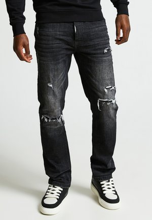 Dunkelblaue Jeans mit geradem Schnitt, ausgestattet mit stylischen zerstörten Details und Rissen an den Knien, kombiniert mit schwarz-weißen High-Top-Sneakern.