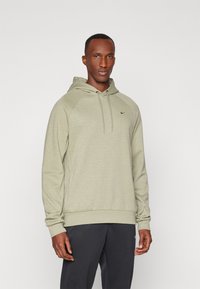 Hoodie vert clair avec cordon de serrage, manches raglan et un petit logo Nike noir sur la poitrine. Fabriqué en tissu doux et texturé.