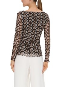 Czarna bluzka z długim rękawem o przezroczystej strukturze, złożona z misternie wykonanego geometrycznego wzoru w bieli, pomarańczy i jasnoniebieskim. Gładki dół.