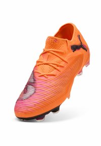 Scarpa da calcio arancione brillante con superficie texturizzata, accenti viola sfumati, logo Puma nero, design con lacci e tacchetti traslucidi.
