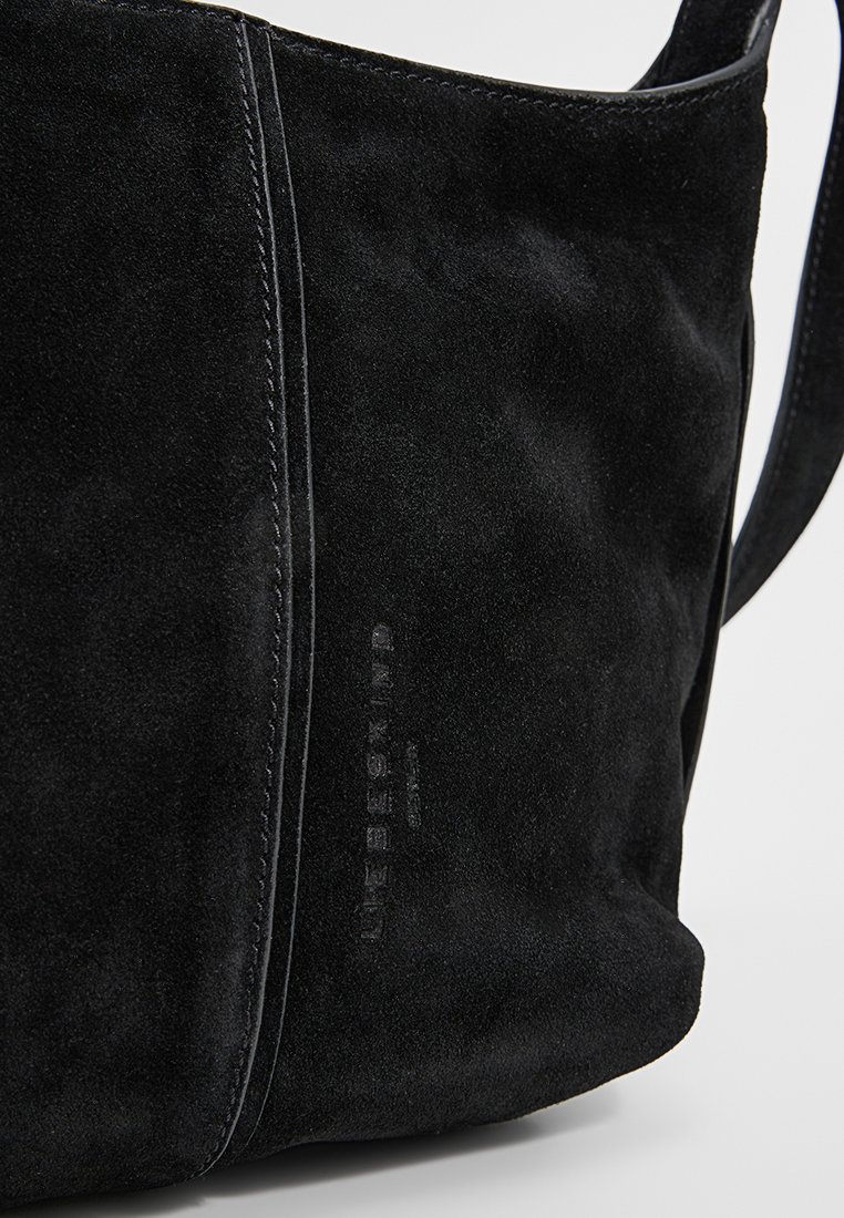 Bolso de hombro de ante negro con una textura suave, que presenta costuras en contraste y el logo de la marca grabado en el lateral.