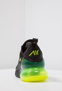 Svart och neongrön Nike Air Max 270-sko visad bakifrån, som framhäver hälkuddens luftfyllning och märkets detaljer.