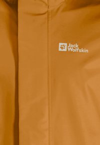 Veste imperméable orange avec une texture lisse, des coutures renforcées et un logo imprimé blanc sur la zone gauche de la poitrine.