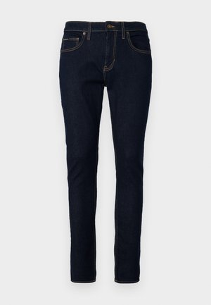 Donkerblauwe denim jeans met een slim fit, voorzien van stiksel details, vijf zakken en een knoopsluiting bij de taille.