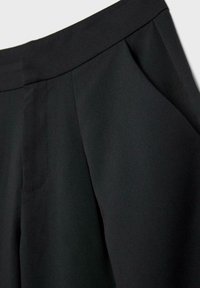 Čierne nohavice na mieru s záhybmi, vybavené bočnými vreckami a hladkou textúrou, navrhnuté s čistým opaskom pre moderný strih.