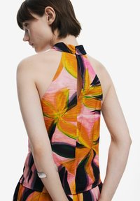 Top a halter colorato con un motivo floreale nei toni di rosa, arancione e nero, caratterizzato da un design a chiave sulla schiena e un tessuto testurizzato.