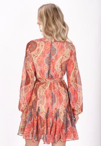 Bloemige paisley-gepatroneerde jurk in doorzichtig materiaal. Heeft lange mouwen, een verstelbare tailleband en een uitlopende rok met plooien. Kleuren zijn oranje, roze en blauw.