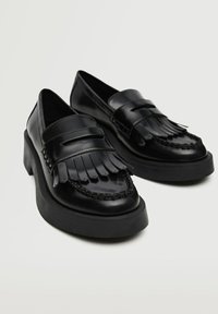 Sorte læder slip-on sko med frynse detaljer, vævede accenter og en chunky gummisål. Glat overflade, rund tåform.