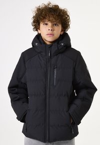 Chaqueta acolchada negra con capucha, que cuenta con bolsillos con cremallera y un diseño acolchado. Fabricada con un tejido duradero y resistente a la intemperie.