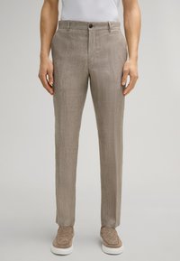 Lichtbruine linnen broeken met een rechte pasvorm, subtiele verticale textuur, knoopsluiting en voorzakken, gecombineerd met een paar beige instapschoenen.