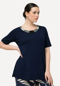 Maglietta blu navy a maniche corte con scollatura decorata con perline in argento, nero e oro; vestibilità comoda con orlo curvo.