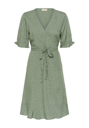 Grön omlottklänning med vita prickar, korta puffärmar, knyt midja och utsvängd nederkant. Tillverkad av ett lätt tyg.