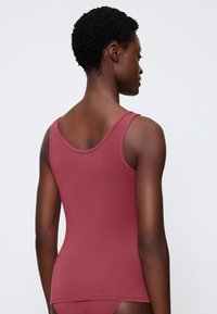 Ribbed, sleeveless tank top in deep rose color. Soft fabric with a fitted design, round neckline, and straight hem.