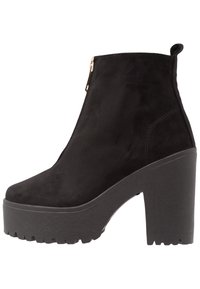 Mustat mokkasiinisaappaat nilkkaketjuilla, joissa on korkea platta ja paksu korko, sivuvetoketju ja teksturoitu kumipohja.