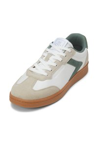 Zapatilla blanca y beige con una superposición de ante, acentos verdes y cordones blancos. Punta redonda y suela de goma texturizada. Logo en la lengüeta.