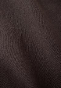 Tissu marron foncé avec une texture sergé diagonale fine et des plis doux.