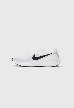 Baskets de sport blanches avec logo Nike swoosh noir, empeigne en mesh et semelle blanche épaisse sur fond gris clair uni.