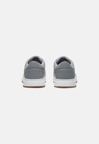 Zapatillas grises con un upper de malla y gamuza, entresuela blanca y suela de goma marrón. Cuenta con un cuello acolchado para mayor comodidad.