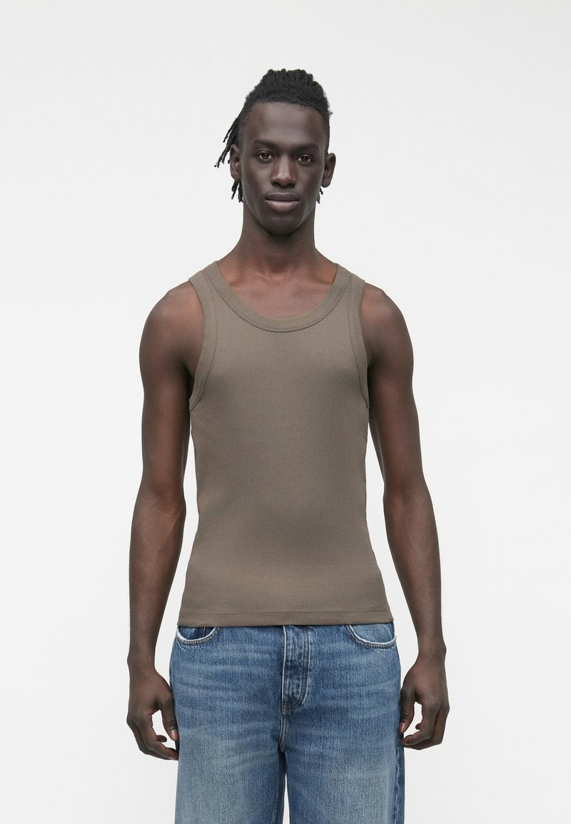 Bruin geribd tanktop met een ronde hals, gedragen met blauwe spijkerbroek. De top heeft een aansluitende pasvorm en een gladde textuur.