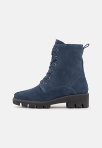 Stivaletti alla caviglia in suede blu navy con punta rotonda, stringatura frontale e suola in gomma con battistrada pronunciato. Linguetta sul retro per facilitare l'indossamento.