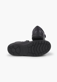 Pantofii din piele neagră au vârful ascuțit, dispun de o talpă din cauciuc texturat și un brâu ajustabil pe mijlocul piciorului pentru o fixare sigură.