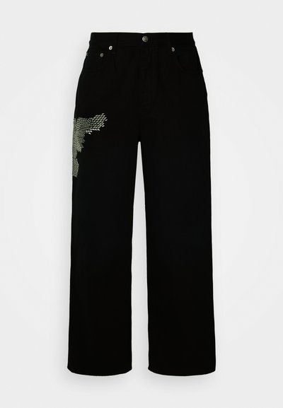 Jeans de pierna ancha negros hechos de denim, con un patrón texturizado en la pierna izquierda y herrajes en tono plateado.