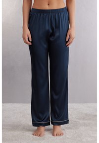 Marineblauwe satijnen pyjamabroek met een elastische tailleband, recht gesneden ontwerp en lichtgekleurde piping aan de boorden. Zachte textuur en gladde afwerking.