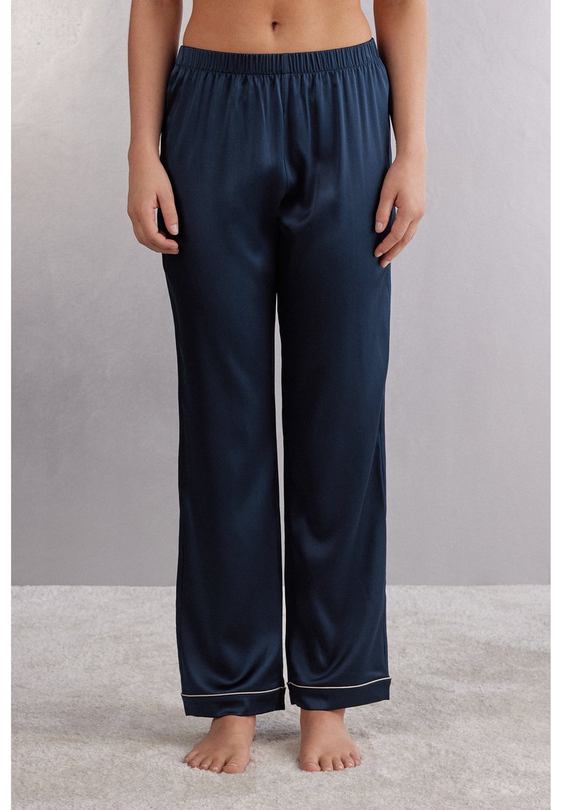 Marineblauwe satijnen pyjamabroek met een elastische tailleband, recht gesneden ontwerp en lichtgekleurde piping aan de boorden. Zachte textuur en gladde afwerking.