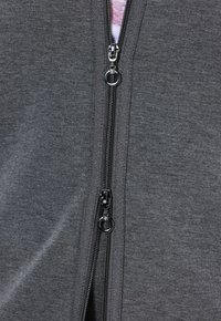 Hoodie gris zippé avec double fermeture éclair en métal à tirettes rondes, ourlet ajustable et tissu doux et texturé pour le confort.