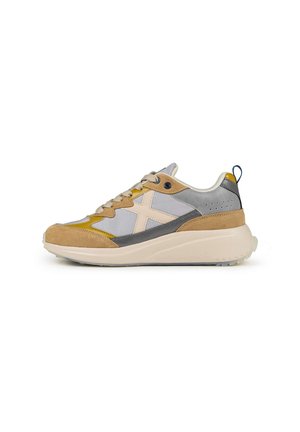 Zapatillas deportivas con una mezcla de materiales de ante y malla en tonos gris, beige y amarillo, con una suela blanca acolchada y una lengüeta trasera.
