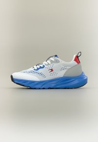 Λευκό αθλητικό παπούτσι με μπλε σόλα, γκρι λεπτομέρειες και κόκκινη λεπτομέρεια στη φτέρνα. Διαθέτει επάνω μέρος από δίχτυ με αεραγωγούς και σύστημα δέσιμου με κορδόνια.