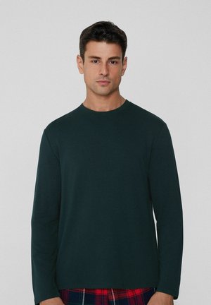 Donkergroen shirt met lange mouwen en een ronde hals. Gladde textuur, eenvoudig ontwerp, gecombineerd met geruite pyjamabroek.