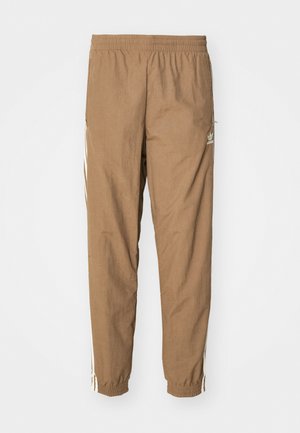 Pantalons de jogging marron en tissu léger, avec une taille élastique, des jambes effilées et des bandes blanches sur les côtés. Pas de poches visibles.