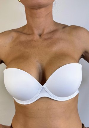 Sujetador blanco sin tirantes con copas moldeadas, textura suave y diseño sin costuras. Presenta un escote bajo para versatilidad bajo la ropa.