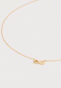 Κολιέ με χρυσή αλυσίδα που διαθέτει μενταγιόν απεικόνισης του άπειρου διακοσμημένο με μικρά κρύσταλλα, με λεία υφή και λεπτούς κρίκους.