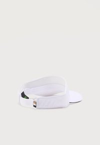 Λευκός ρυθμιζόμενος αθλητικός σκούφος με διάτρητο πίσω λουράκι και μικρή ετικέτα επωνυμίας σε απλό φωτεινό φόντο.