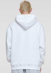 Witte hoodie met een ruime pasvorm, trekkoord capuchon en ribgebreide manchetten bij de mouwen en onderrand. Zachte stof met minimale details.