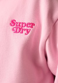 Sudadera rosa con una textura suave, que presenta un logo bordado de "Super Dry" en un tono rosa contrastante.