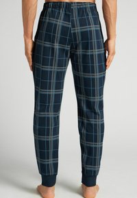 Marineblauwe plaid joggerbroek met een zachte textuur, voorzien van lichtblauwe en grijze ruitpatronen, elastische tailleband en aangesloten boorden bij de enkels.