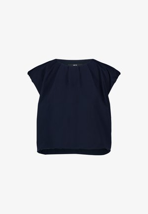 Blouse bleu marine à manches courtes avec encolure froncée et coupe ample, étiquette "zero" visible au niveau du col.