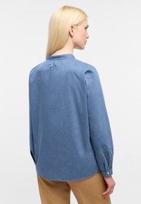Lys blå chambray skjorte med lange ærmer, en lille krave og knapmanchetter. Tekstureret stof og en afslappet pasform. Rund søm i ryggen.