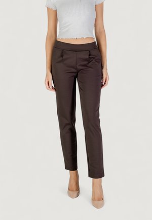 Pantaloni beige su misura con una texture liscia, dotati di una vita aderente e pieghe delicate. Abbinati a tacchi alti color nude.